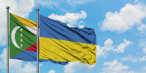 Comoros and Ukraine flag waving in the wind against white cloudy blue sky together. Diplomacy concept, international relations.