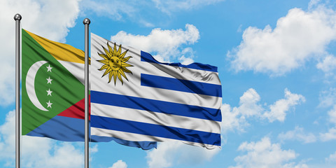 Comoros and Uruguay flag waving in the wind against white cloudy blue sky together. Diplomacy concept, international relations.