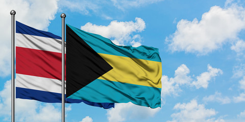 Costa Rica and Bahamas flag waving in the wind against white cloudy blue sky together. Diplomacy concept, international relations.