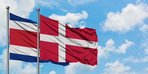 Costa Rica and Denmark flag waving in the wind against white cloudy blue sky together. Diplomacy concept, international relations.