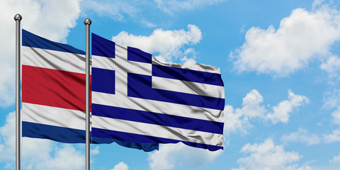 Costa Rica and Greece flag waving in the wind against white cloudy blue sky together. Diplomacy concept, international relations.