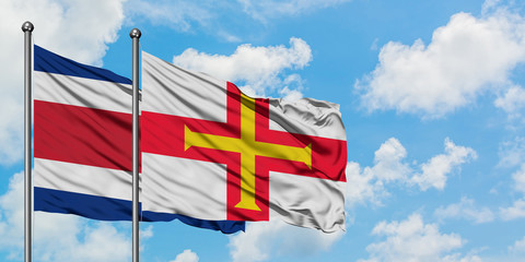 Costa Rica and Guernsey flag waving in the wind against white cloudy blue sky together. Diplomacy concept, international relations.