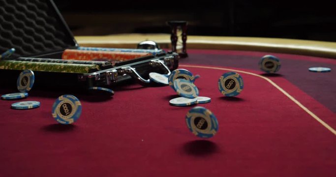 Poker table with poker chips in suitcase and falling on the table in casino. Poker chips for gambling card game.