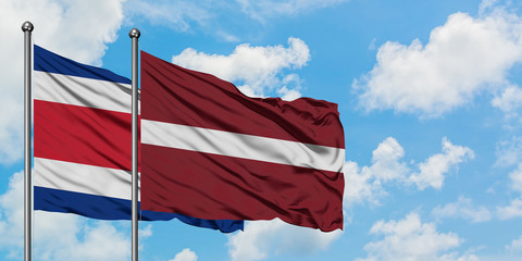 Costa Rica and Latvia flag waving in the wind against white cloudy blue sky together. Diplomacy concept, international relations.
