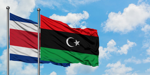 Costa Rica and Libya flag waving in the wind against white cloudy blue sky together. Diplomacy concept, international relations.