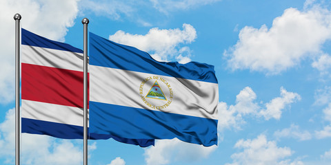 Costa Rica and Nicaragua flag waving in the wind against white cloudy blue sky together. Diplomacy concept, international relations.