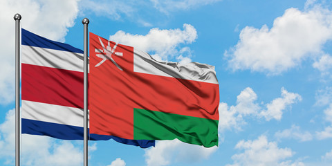 Costa Rica and Oman flag waving in the wind against white cloudy blue sky together. Diplomacy concept, international relations.