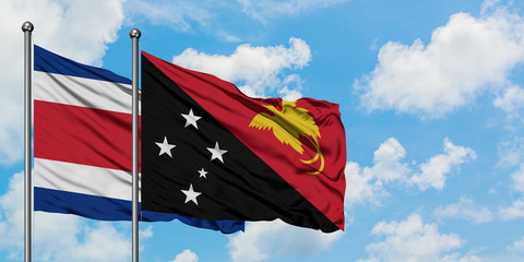 Costa Rica and Papua New Guinea flag waving in the wind against white cloudy blue sky together. Diplomacy concept, international relations.