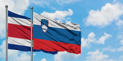 Costa Rica and Slovenia flag waving in the wind against white cloudy blue sky together. Diplomacy concept, international relations.