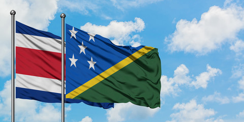 Costa Rica and Solomon Islands flag waving in the wind against white cloudy blue sky together. Diplomacy concept, international relations.