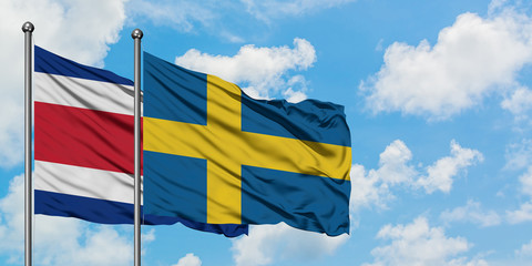 Costa Rica and Sweden flag waving in the wind against white cloudy blue sky together. Diplomacy concept, international relations.