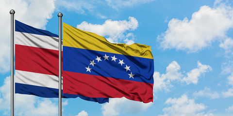 Costa Rica and Venezuela flag waving in the wind against white cloudy blue sky together. Diplomacy concept, international relations.