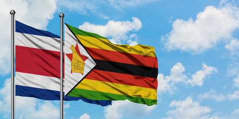 Costa Rica and Zimbabwe flag waving in the wind against white cloudy blue sky together. Diplomacy concept, international relations.