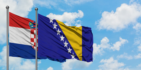 Croatia and Bosnia Herzegovina flag waving in the wind against white cloudy blue sky together. Diplomacy concept, international relations.