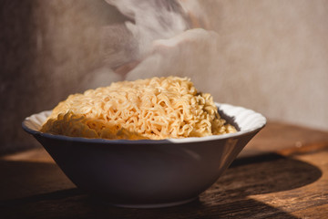 The smoke was poured from the boiled instant yellow noodles that had been boiled in hot water and brought out from a boiling pot in a bowl to be prepared as a food menu.