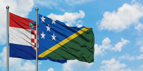 Croatia and Solomon Islands flag waving in the wind against white cloudy blue sky together....