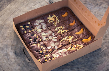 Fudge brownies in a brown paper box on wooden table