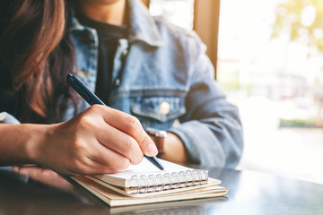 Closeup image of a woman writing on a blank notebook on the table