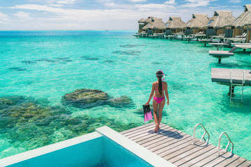 Luxury overwater bungalows Tahiti resort woman going snorkeling from private hotel room on Bora Bora island, French Polynesia. Travel vacation recreational activity watersport fun leisure. - obrazy, fototapety, plakaty