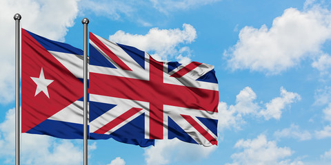 Cuba and United Kingdom flag waving in the wind against white cloudy blue sky together. Diplomacy concept, international relations.