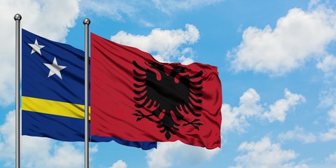 Curacao and Albania flag waving in the wind against white cloudy blue sky together. Diplomacy concept, international relations.