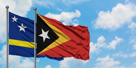 Curacao and East Timor flag waving in the wind against white cloudy blue sky together. Diplomacy concept, international relations.