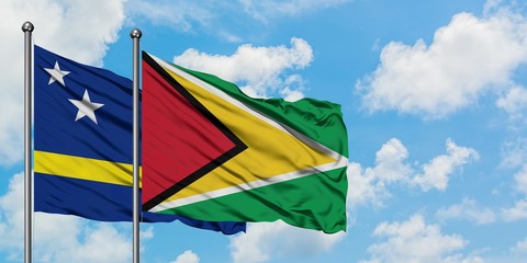 Curacao and Guyana flag waving in the wind against white cloudy blue sky together. Diplomacy concept, international relations.
