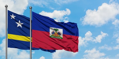 Curacao and Haiti flag waving in the wind against white cloudy blue sky together. Diplomacy concept, international relations.