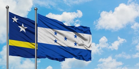 Curacao and Honduras flag waving in the wind against white cloudy blue sky together. Diplomacy concept, international relations.