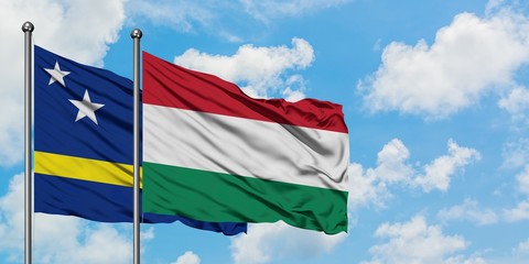 Curacao and Hungary flag waving in the wind against white cloudy blue sky together. Diplomacy concept, international relations.