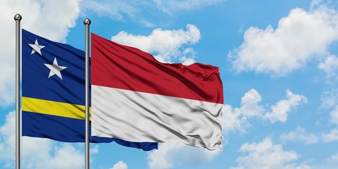 Curacao and Indonesia flag waving in the wind against white cloudy blue sky together. Diplomacy concept, international relations.