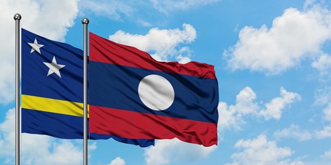 Curacao and Laos flag waving in the wind against white cloudy blue sky together. Diplomacy concept, international relations.
