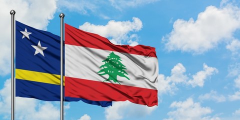 Curacao and Lebanon flag waving in the wind against white cloudy blue sky together. Diplomacy concept, international relations.
