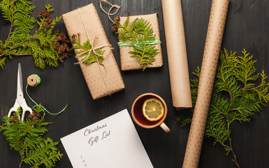 Preparing for the Christmas holidays. Gift wrapping. Christmas Gift List on dark wooden background