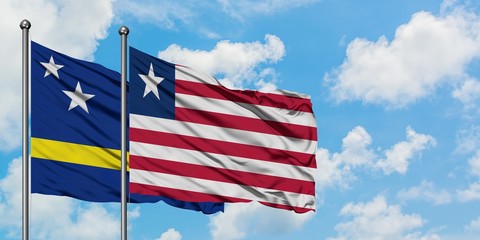 Curacao and Liberia flag waving in the wind against white cloudy blue sky together. Diplomacy concept, international relations.