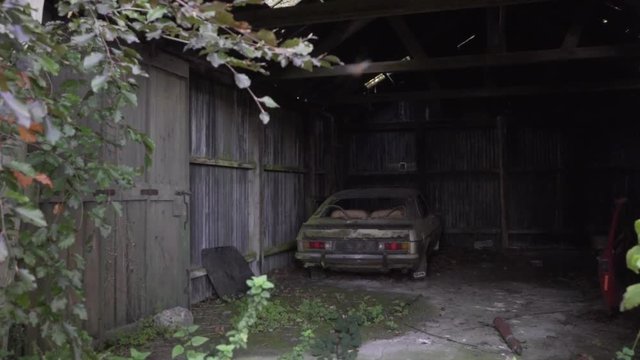 old abandoned and rusty car in farm barn in UK countryside