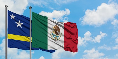 Curacao and Mexico flag waving in the wind against white cloudy blue sky together. Diplomacy concept, international relations.