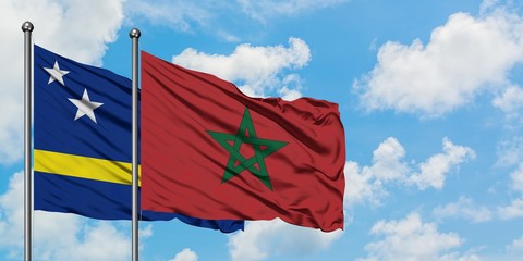 Curacao and Morocco flag waving in the wind against white cloudy blue sky together. Diplomacy concept, international relations.