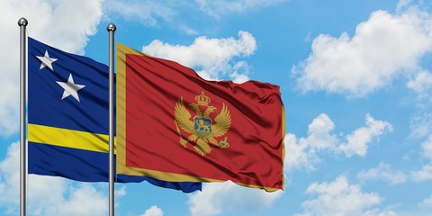 Curacao and Montenegro flag waving in the wind against white cloudy blue sky together. Diplomacy concept, international relations.