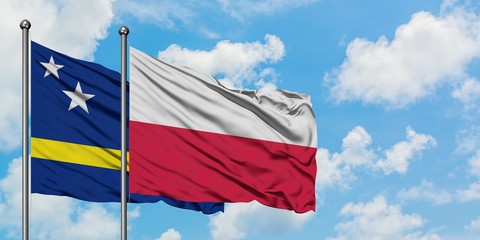 Curacao and Poland flag waving in the wind against white cloudy blue sky together. Diplomacy concept, international relations.