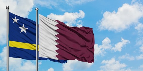 Curacao and Qatar flag waving in the wind against white cloudy blue sky together. Diplomacy concept, international relations.