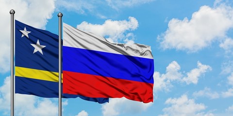 Curacao and Russia flag waving in the wind against white cloudy blue sky together. Diplomacy concept, international relations.
