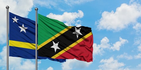 Curacao and Saint Kitts And Nevis flag waving in the wind against white cloudy blue sky together. Diplomacy concept, international relations.