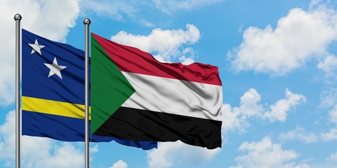 Curacao and Sudan flag waving in the wind against white cloudy blue sky together. Diplomacy concept, international relations.