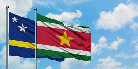 Curacao and Suriname flag waving in the wind against white cloudy blue sky together. Diplomacy concept, international relations.