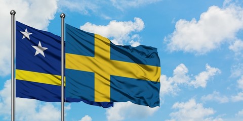 Curacao and Sweden flag waving in the wind against white cloudy blue sky together. Diplomacy concept, international relations.