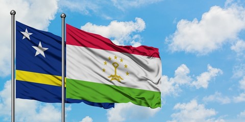 Curacao and Tajikistan flag waving in the wind against white cloudy blue sky together. Diplomacy concept, international relations.