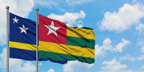Curacao and Togo flag waving in the wind against white cloudy blue sky together. Diplomacy concept, international relations.