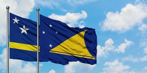 Curacao and Tokelau flag waving in the wind against white cloudy blue sky together. Diplomacy concept, international relations.