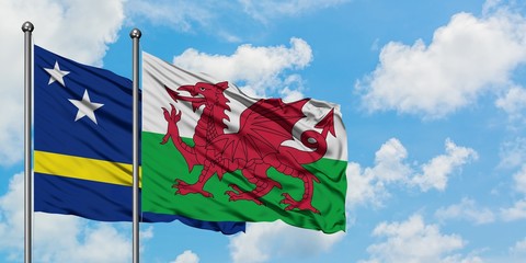 Curacao and Wales flag waving in the wind against white cloudy blue sky together. Diplomacy concept, international relations.